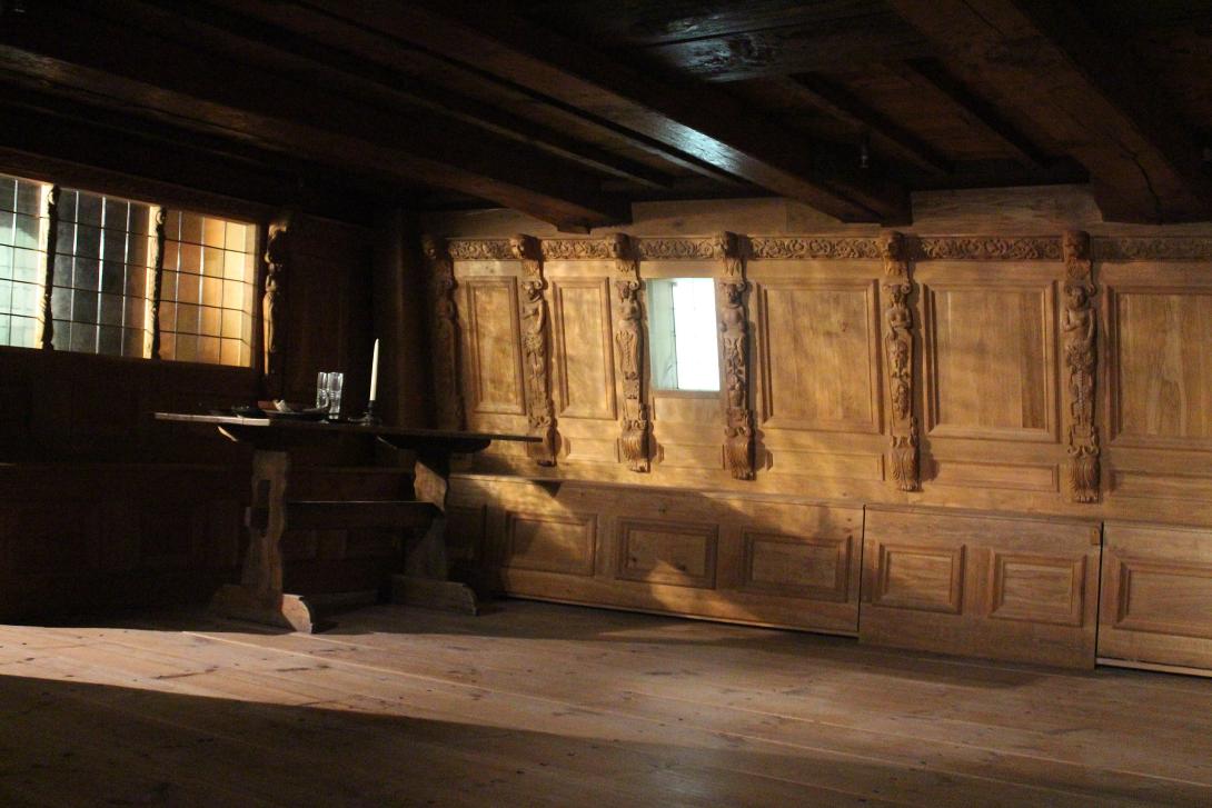 An empty wooden cabin on a ship. It is mostly empty with a small desk in the corner.