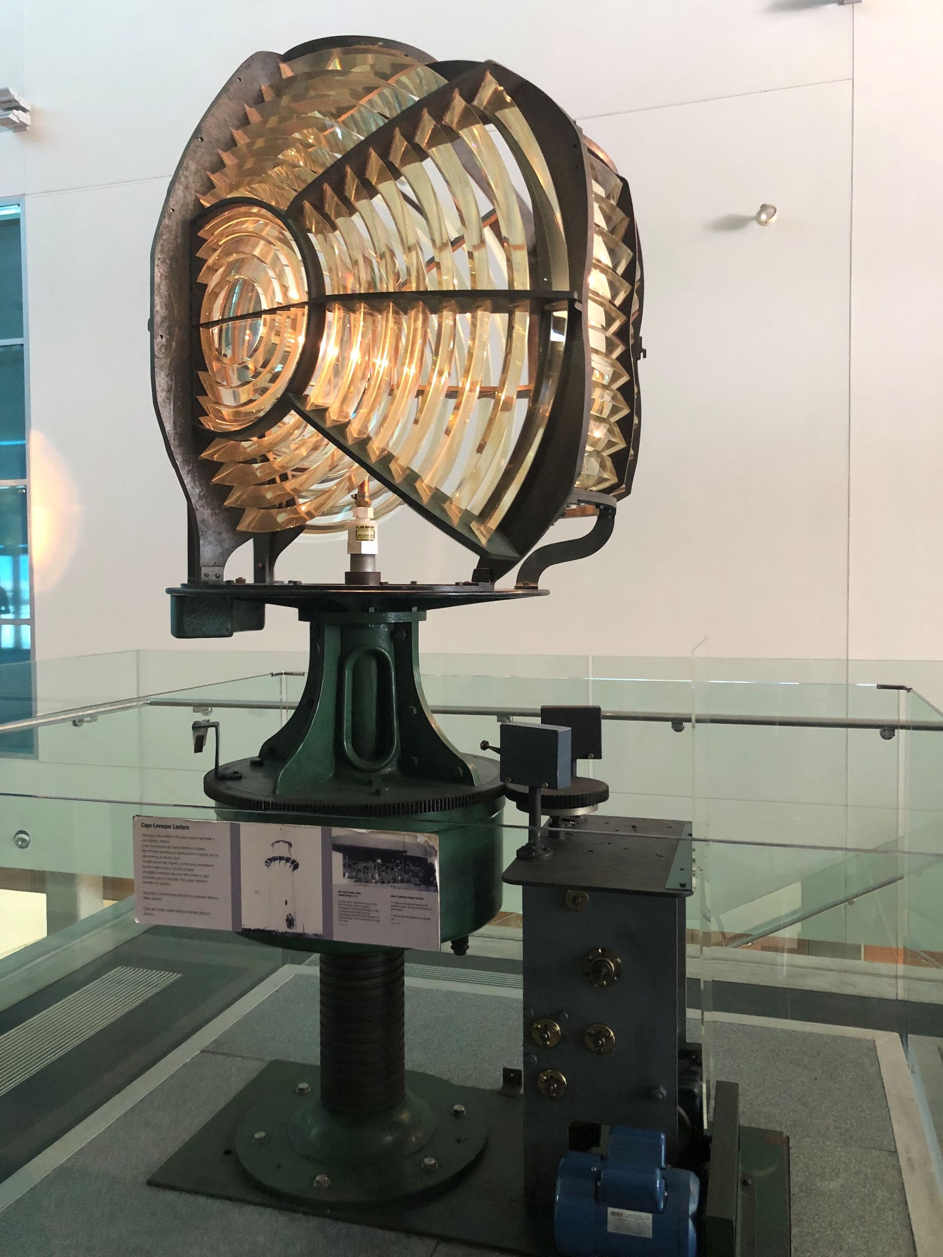 A large lighthouse lens mounted between the Museum stairs and elevator.