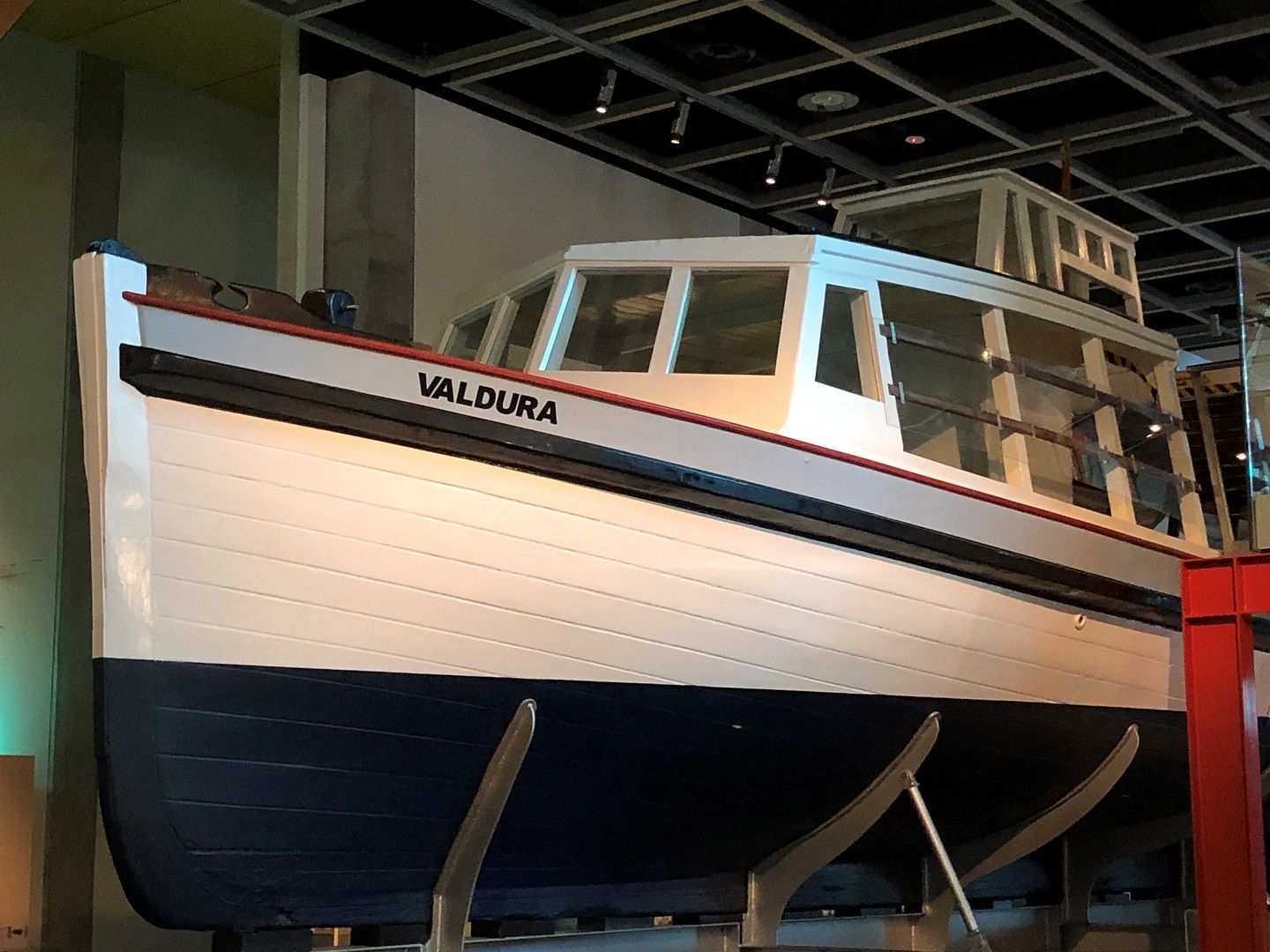 A wooden ferry, its hull painted white and black, suspended next to the walkway.