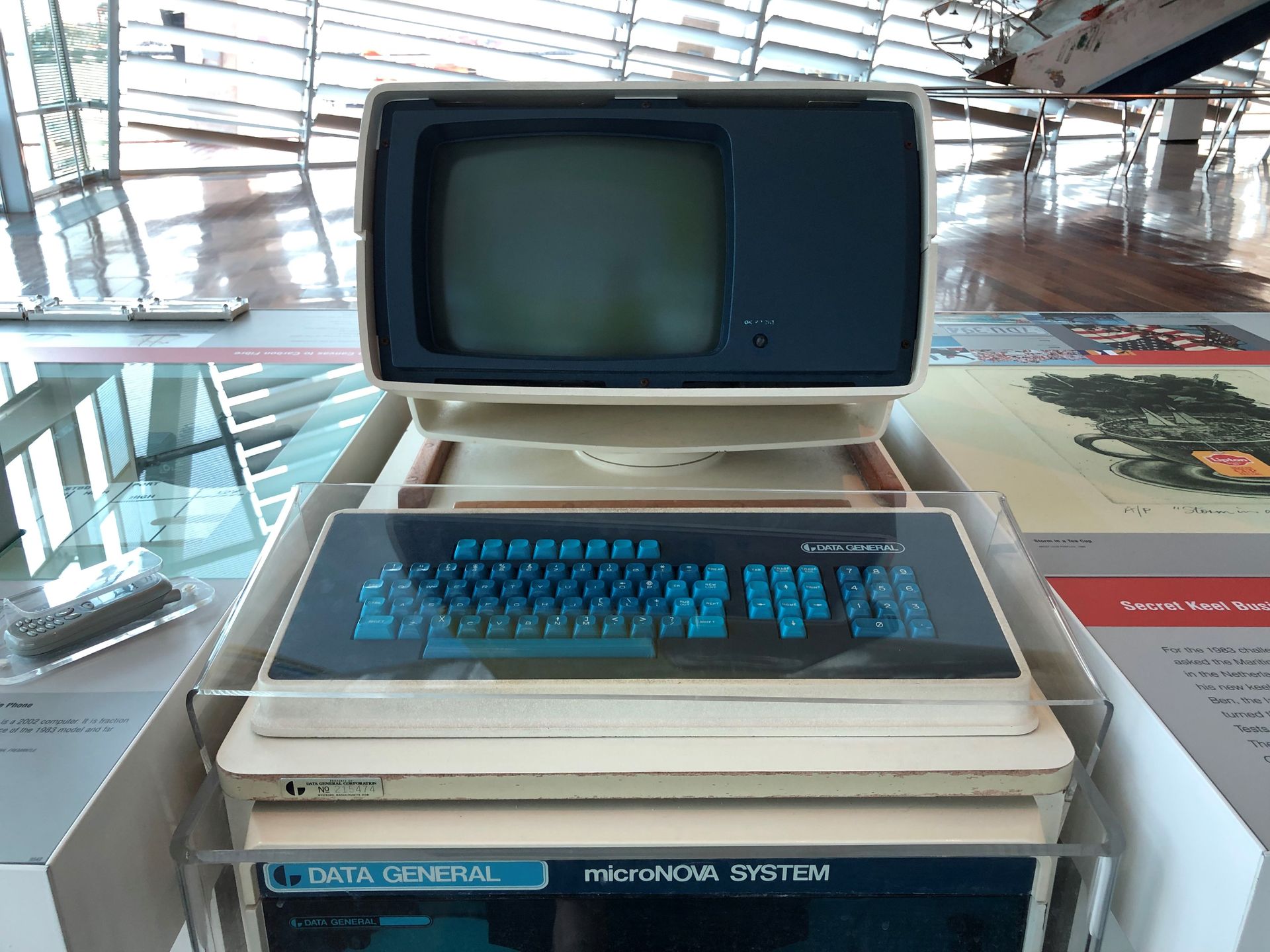 A 1980s computer mounted next to a glass display case, beneath the Australia II.