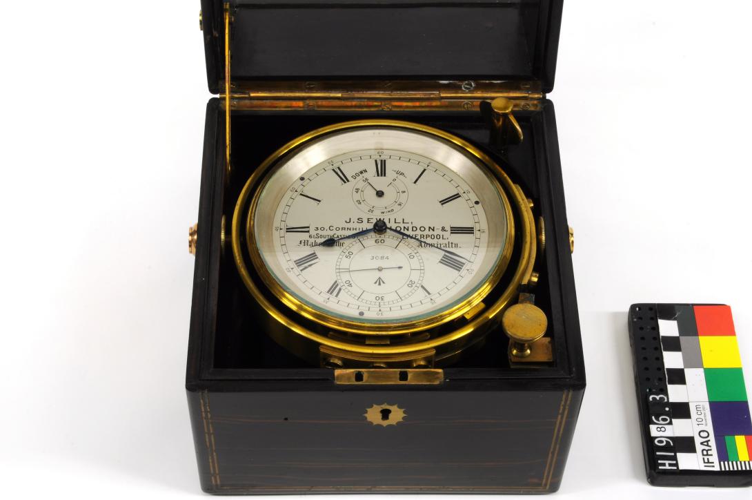 Clock face with a polished brass rim, in a black wooden box.