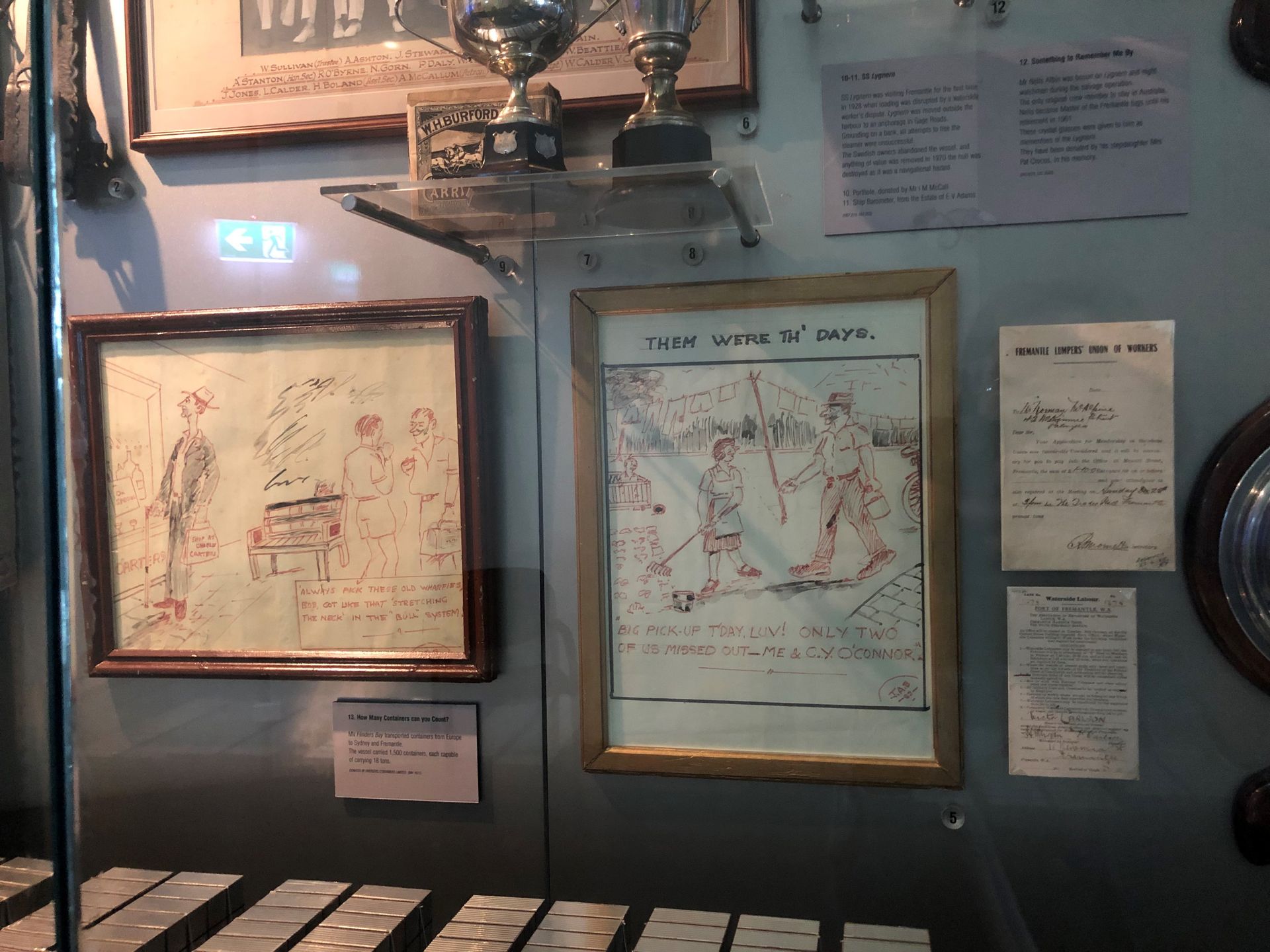 A display cabinet showing hand-drawn posters and documents.