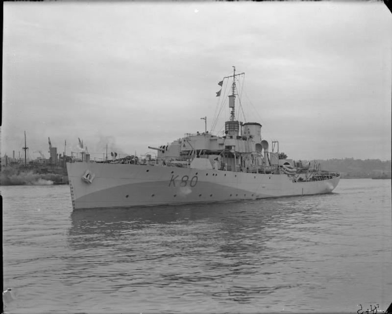 Black and white photo of a warship sailing on a river.