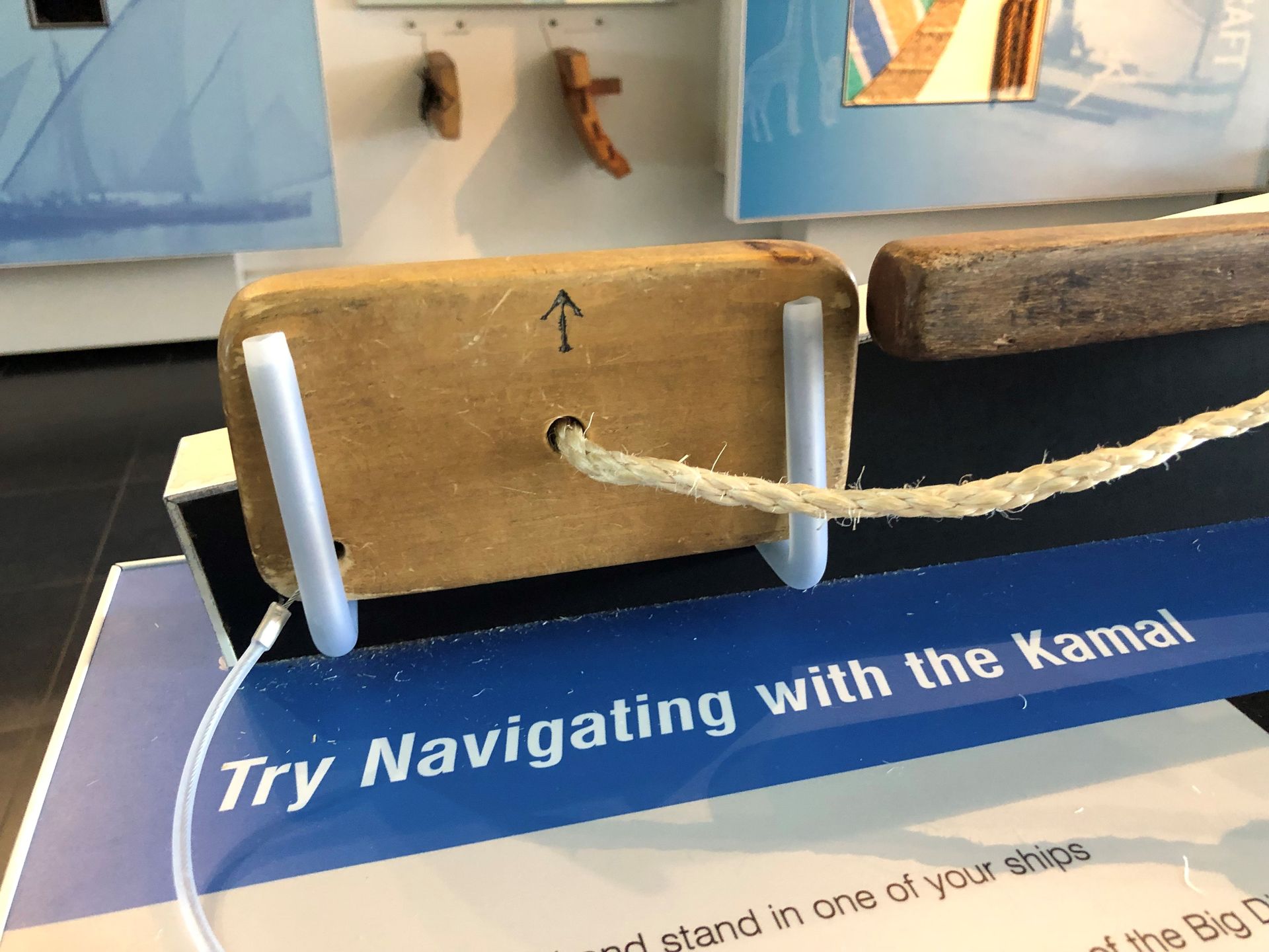 A rectangular wooden block with a rope through the centre. It sits on a display labelled 'try navigating with a kamal.'