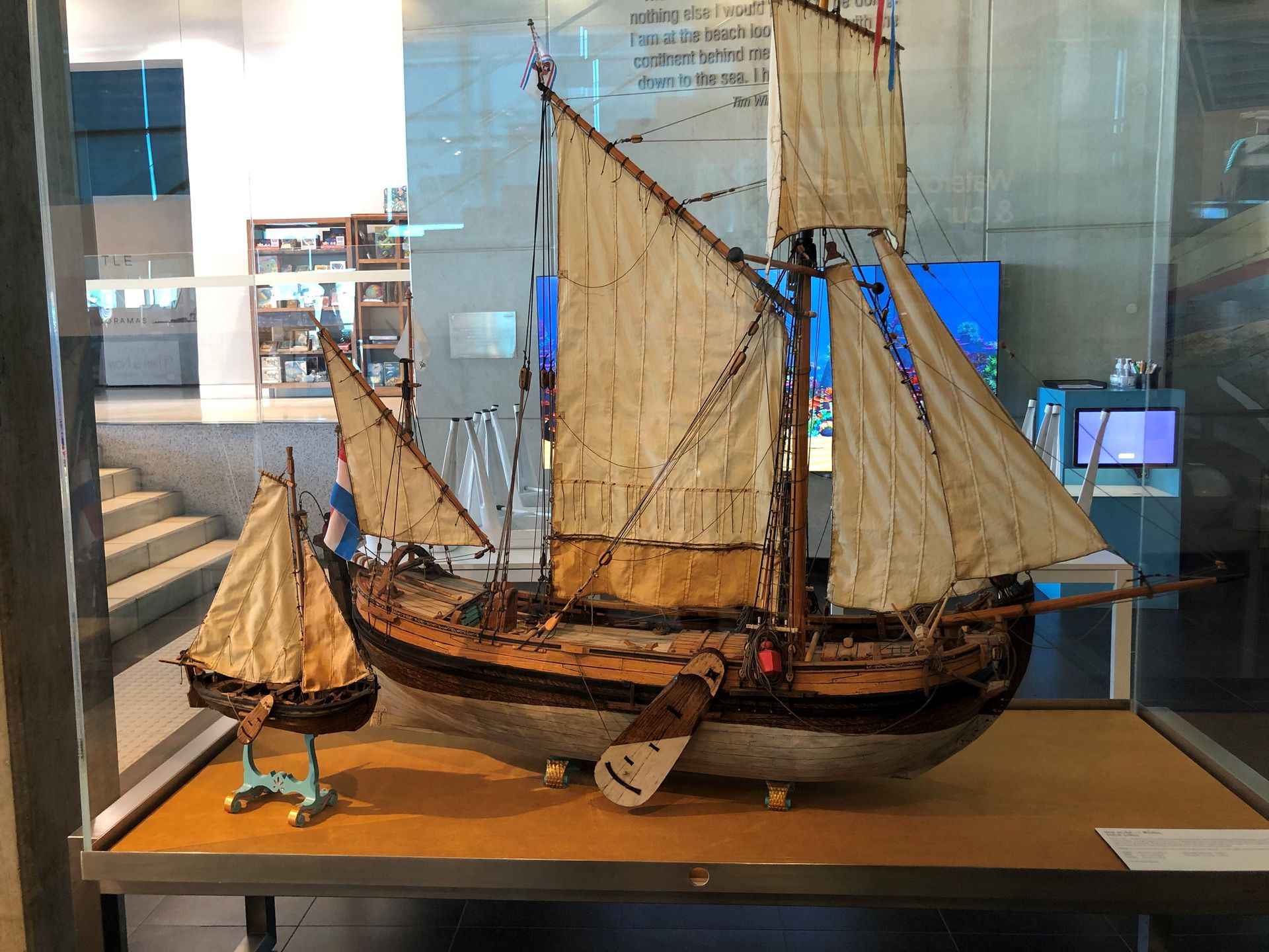 A model of a wooden sailing ship on display in a glass case.